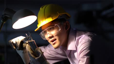 joven ingeniero asiático que trabaja y utiliza herramientas de medición de la calidad de las piezas metálicas. hombre que usa casco de seguridad con taller de trabajo. concepto de ingeniería, carrera, industria, fabricación, seguridad