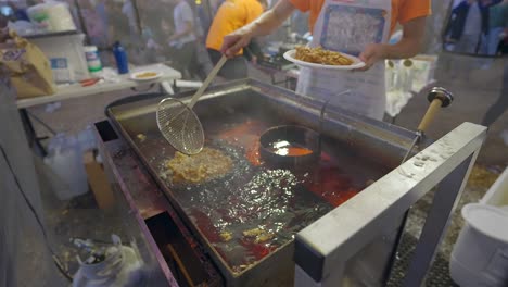 Young-caucasian-boy-flipping-a-funnel-cake-in-a-deep-fryer-at-a-festival