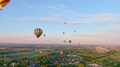 Hot-air-balloons-soar-over-a-tranquil-rural-setting,-bathed-in-the-warm-glow-of-morning-light