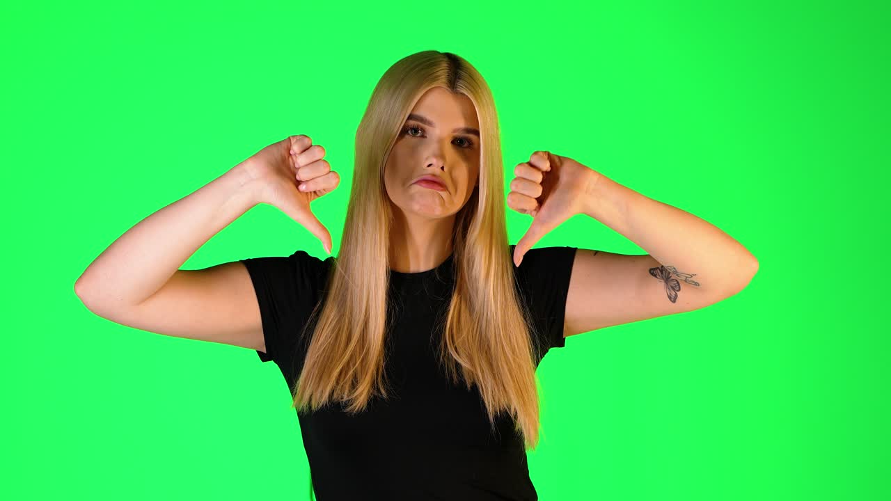 Pretty Blonde Woman Thumbs Down Gesture, Studio Portrait With Green Background