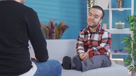 a young man with dwarfism is chatting with his friend at home. close and happy friendship.