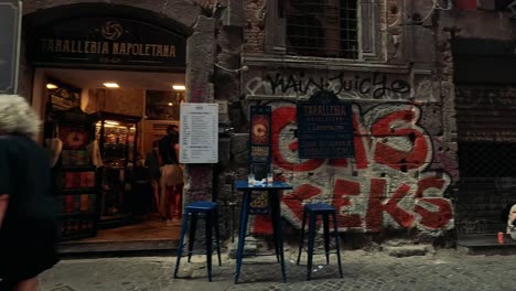 people passing by a graffiti-covered cafe