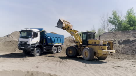 dump truck and loader loading sand