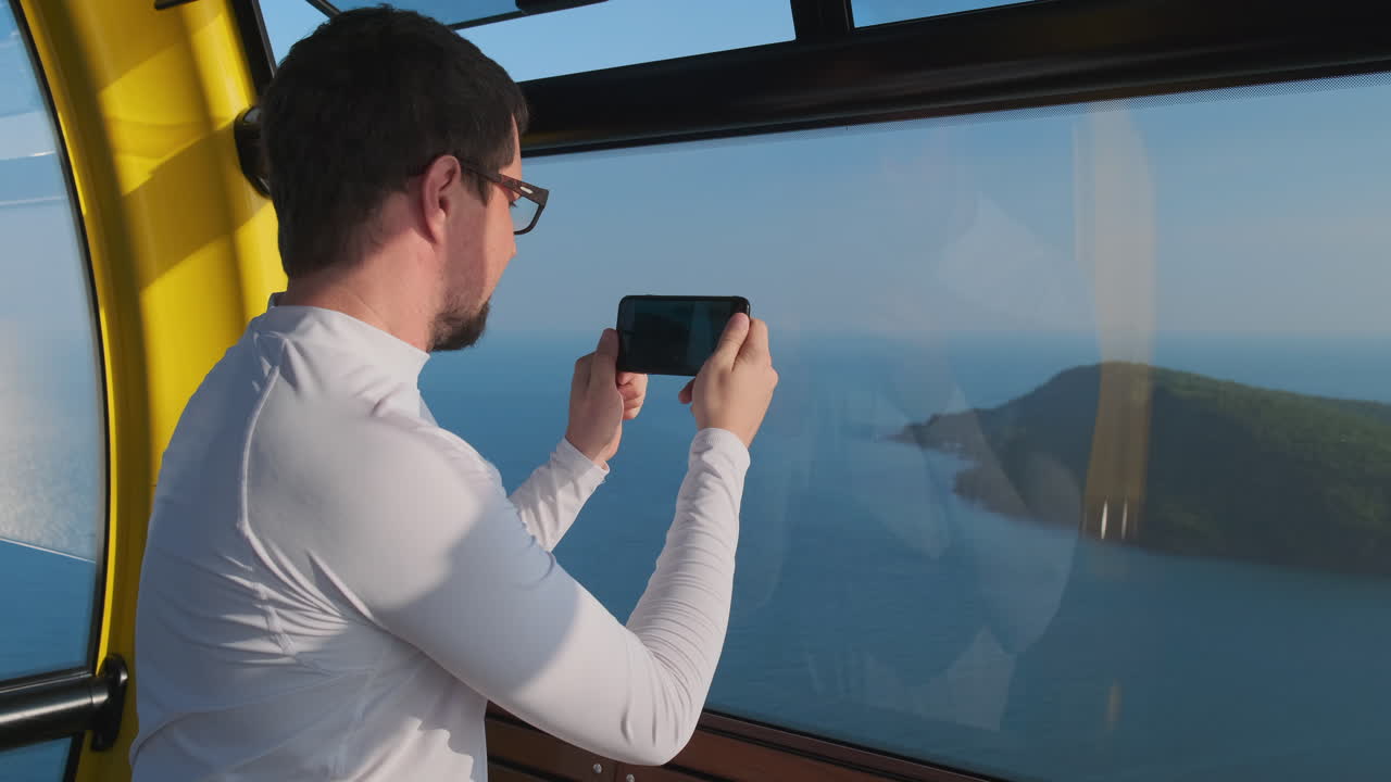 hombre tomando una foto de la vista del océano desde una cabaña