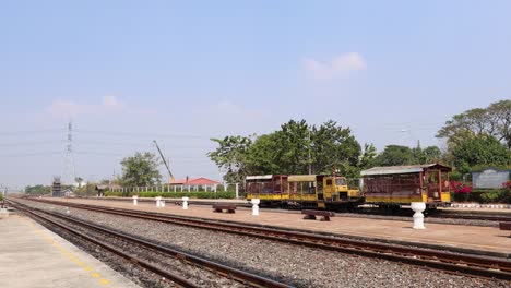 a train moves past a quiet, sunny station