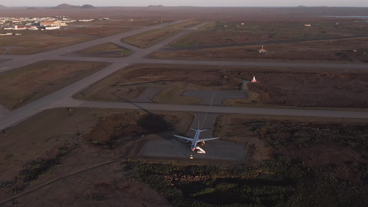 un avión boeing 757 solitario estacionado en el asfalto en un campo abierto en islandia, aéreo