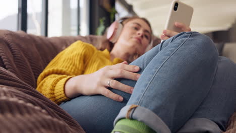 woman relaxing with phone and headphones on a beanbag