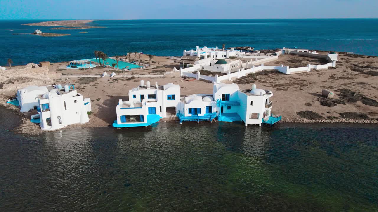 An aerial view of el biben island with a pool and hosting houses sits in the middle of the ocean with palm trees on it, surrounded by water creating a beautiful atmosphere