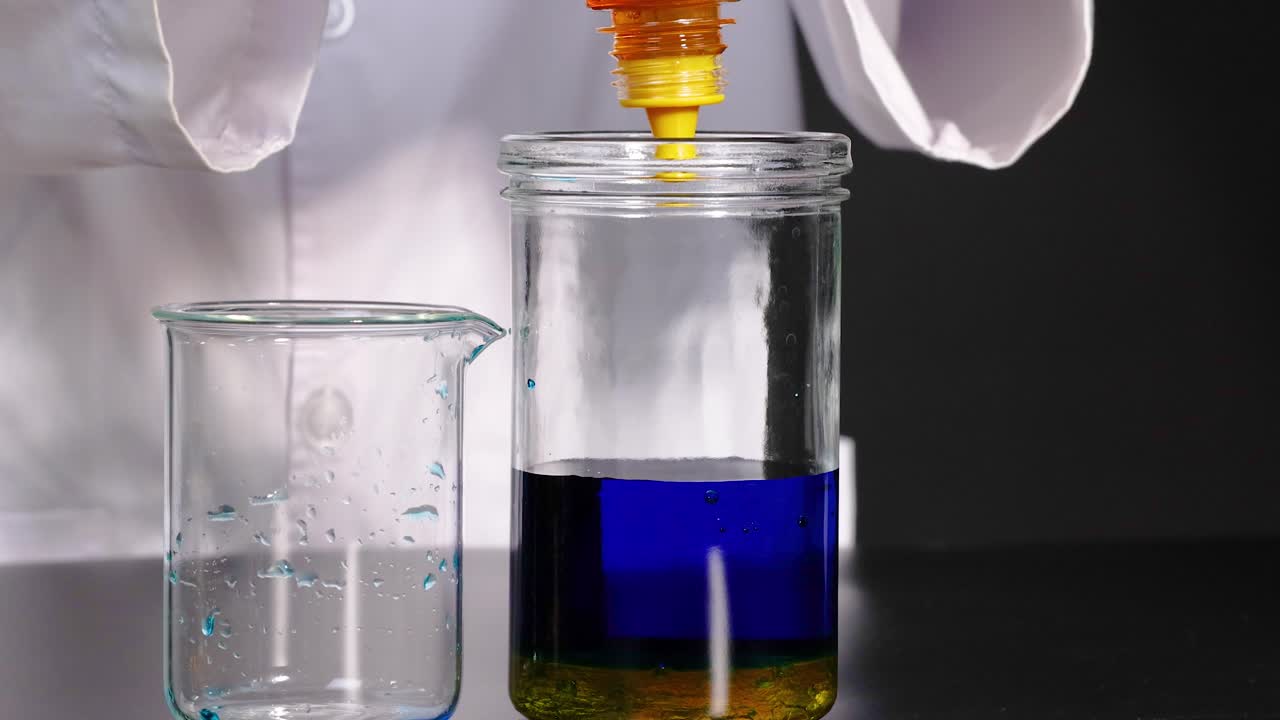 una persona con una bata de laboratorio vierte miel en un frasco que contiene líquido azul, demostrando diferencias de densidad