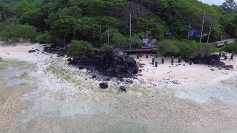 semi orbit around dark rocks and tropical trees on a remote beach in gili trawangan
