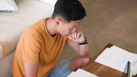 young man reviewing documents at home, focusing on paperwork at wooden table