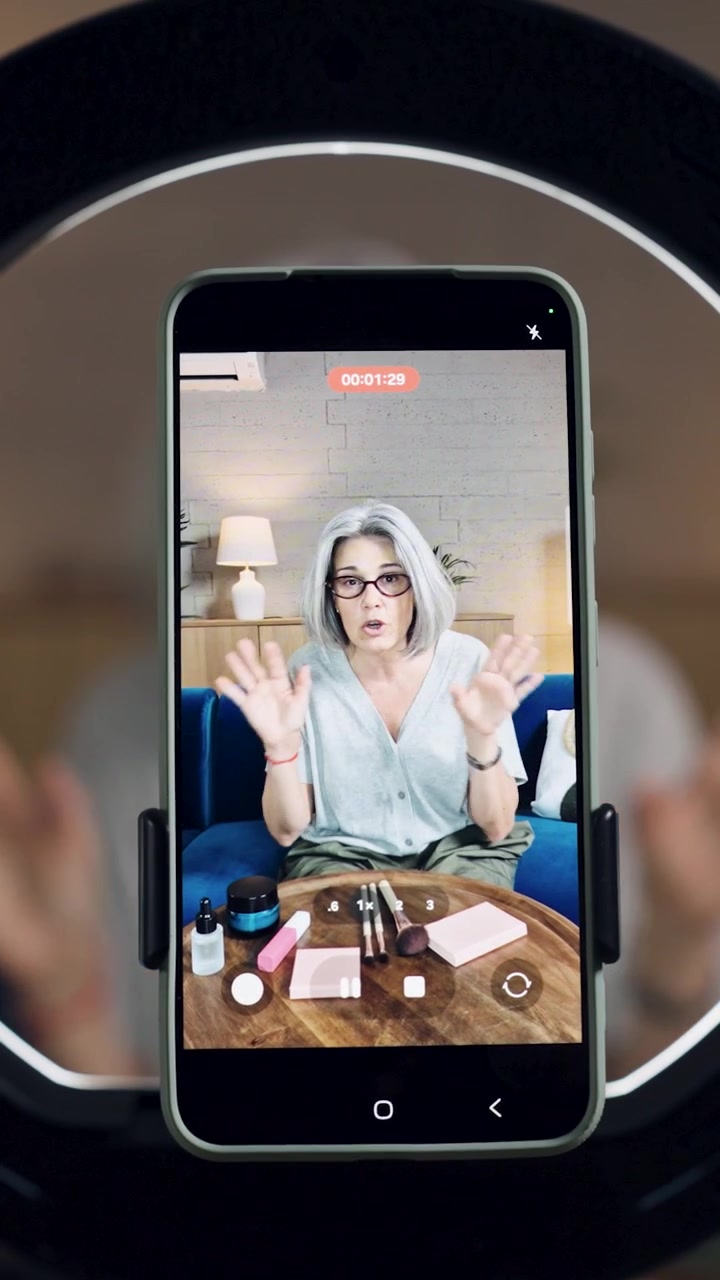Donna matura che registra un video tutorial di bellezza su smartphone