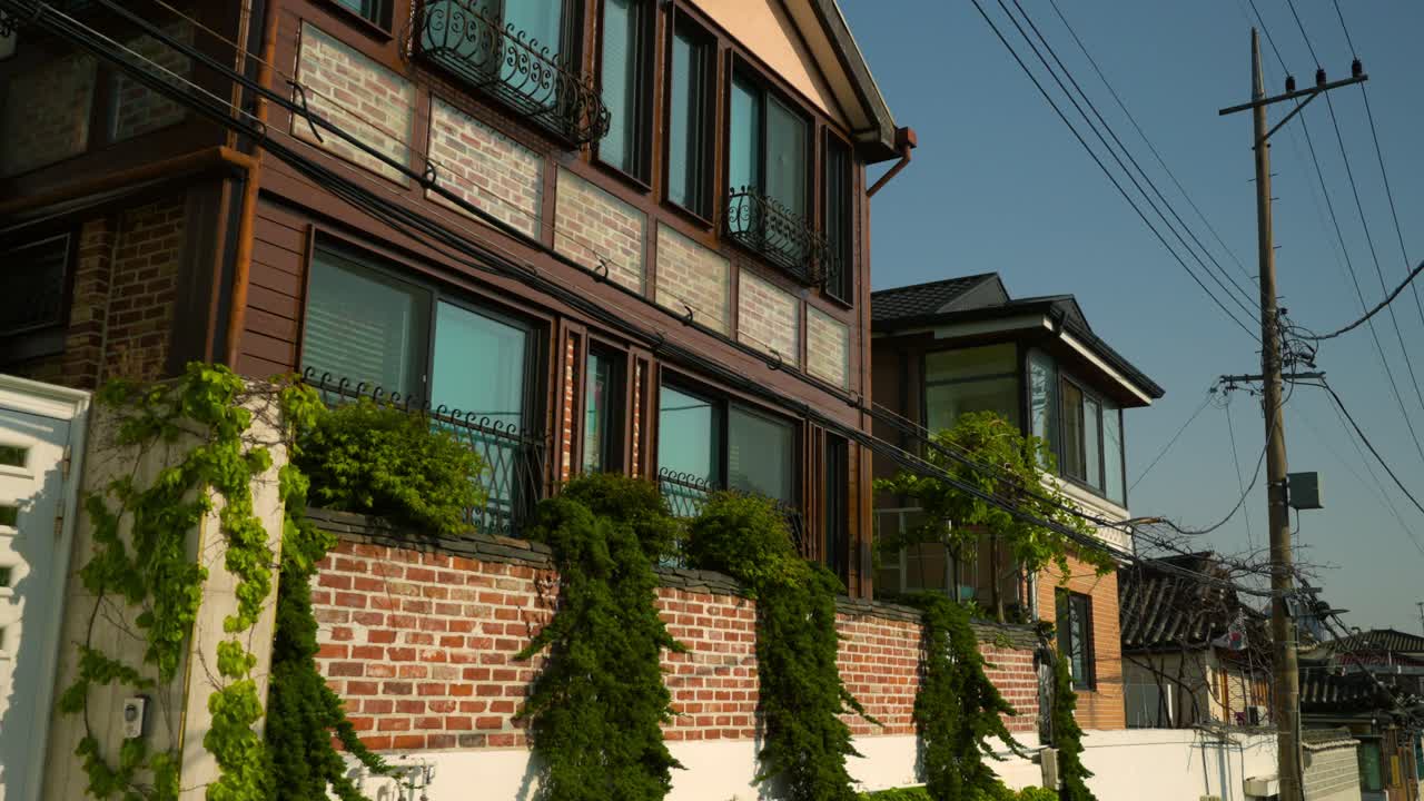 Push-in shot of old Korean villas with brick and wood facades, large windows, and climbing vines in Bukchon Hanok Village, Jongno-gu, Seoul. Push-in