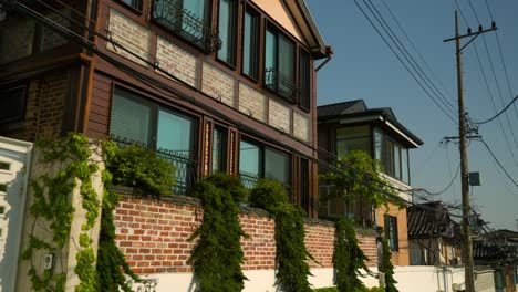 push-in shot of old korean villas with brick and wood facades, large windows, and climbing vines in bukchon hanok village, jongno-gu, seoul. push-in