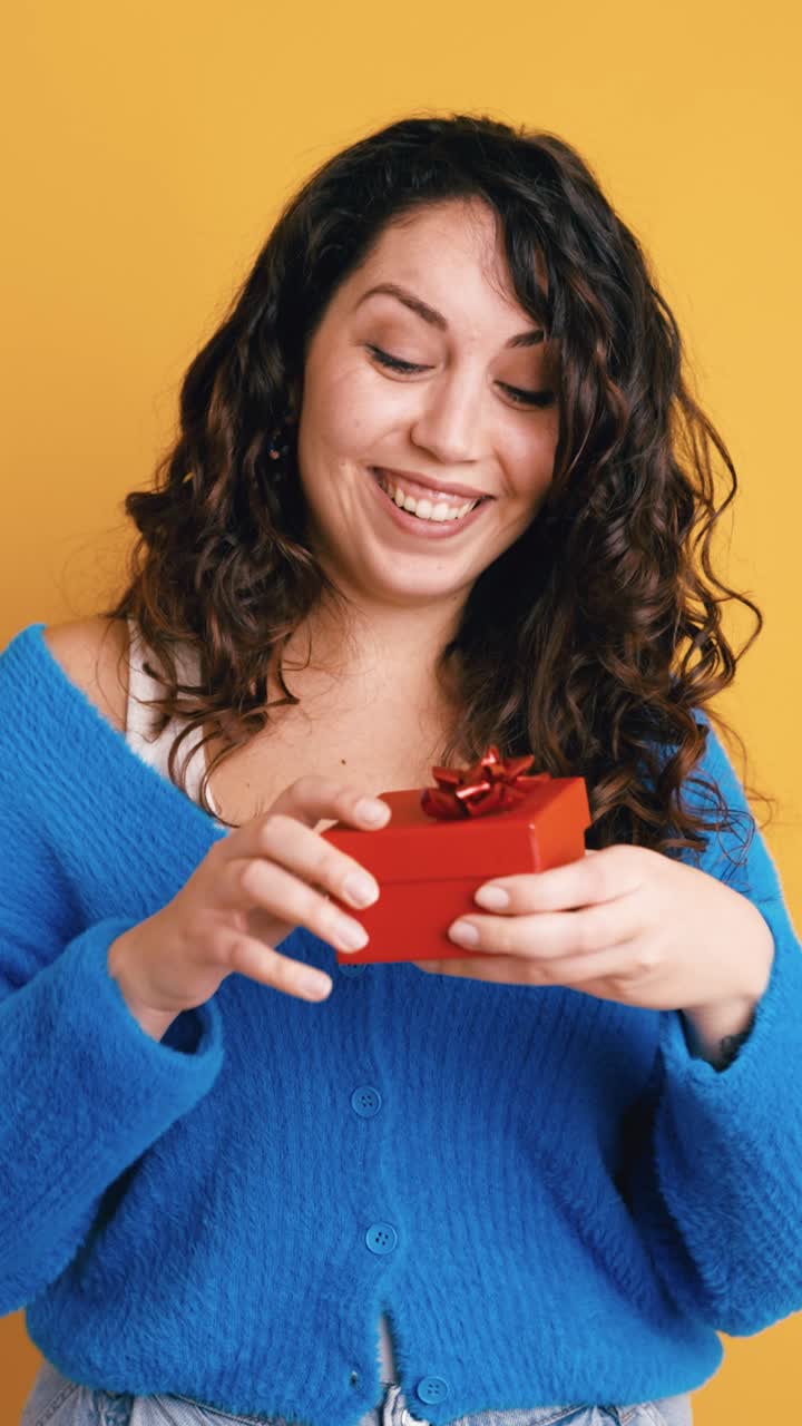 Giovane donna sorpresa che apre una piccola scatola regalo rossa