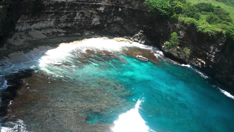 descripción general del agua rompiendo contra los acantilados de la playa rota, nusa penida, bali.