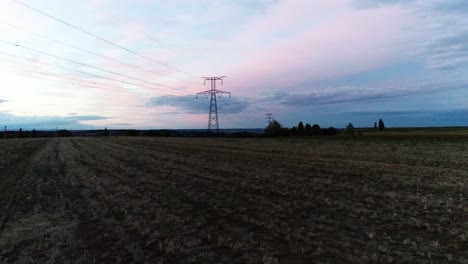 Drone-footage-of-a-sunrise-from-a-farm-field-with-an-electric-power-pole