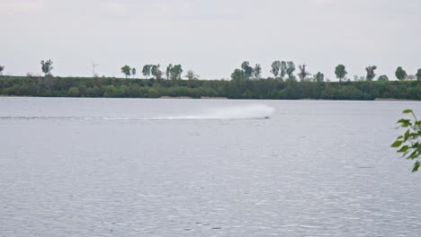 Una-Lancha-Rápida-Maniobrando-A-Través-Del-Lago,-Creando-Un-Chorro-De-Agua-Blanca-A-Su-Paso---Toma-Amplia