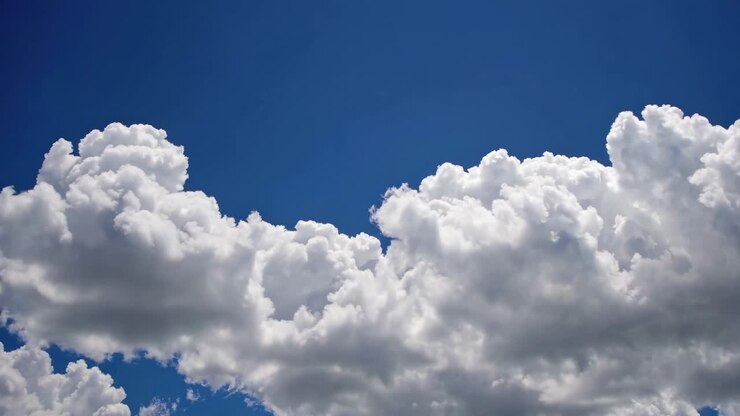 Video captures fluffy white clouds against a deep blue sky from a low-angle perspective