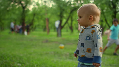 Focused-toddler-standing-outside.-Happy-mother-and-son-playing-with-ball-in-park