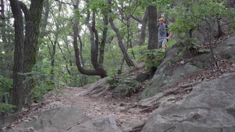 man hiker climbs down a rocky mountain with narrow path - medium shot, hiking concept low angle view