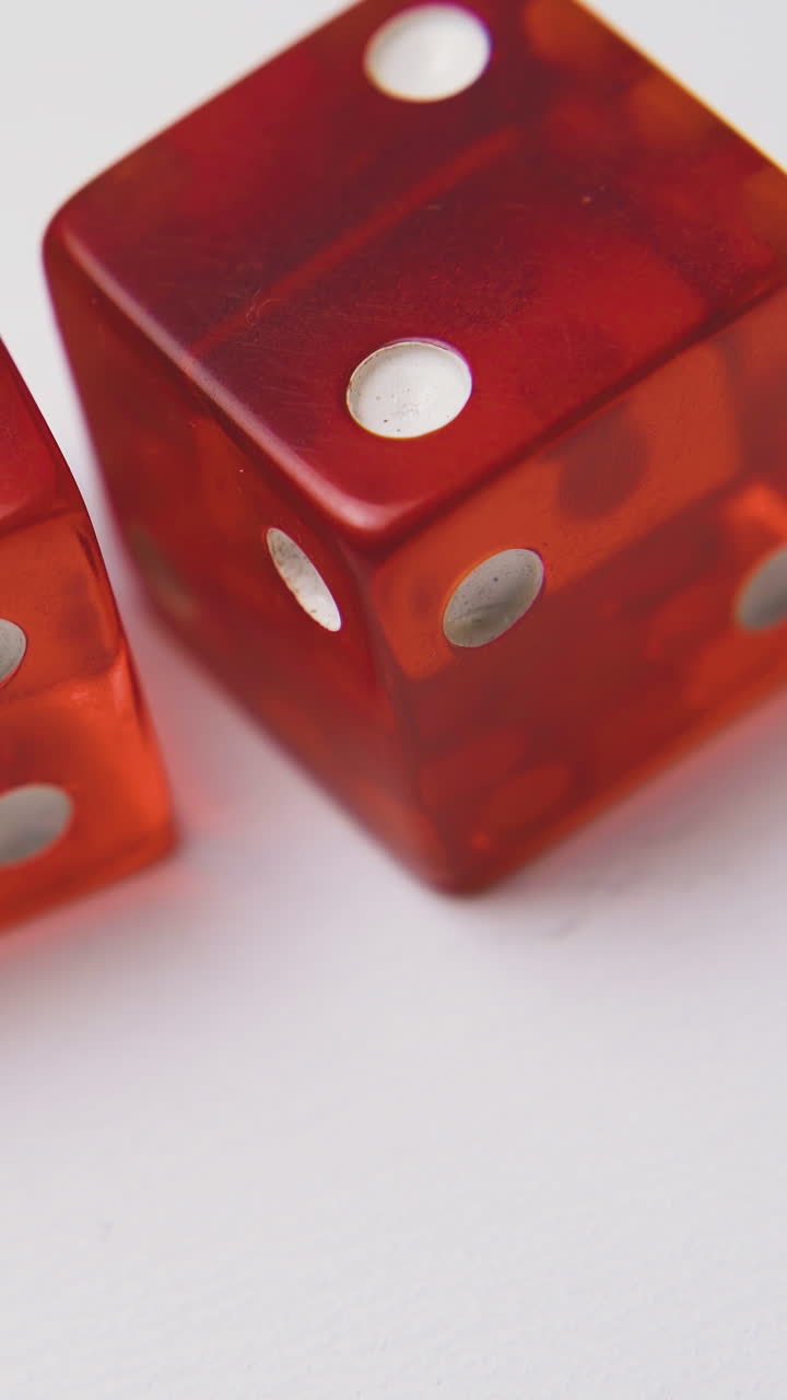 throwing elegant red transparent plastic dices with white spots by man on light surface macro