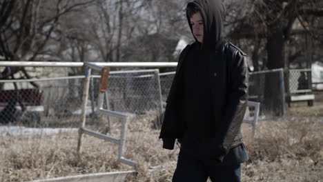 un joven adolescente de secundaria que lleva una mochila caminando por una carretera durante el invierno en un día frío en cámara lenta