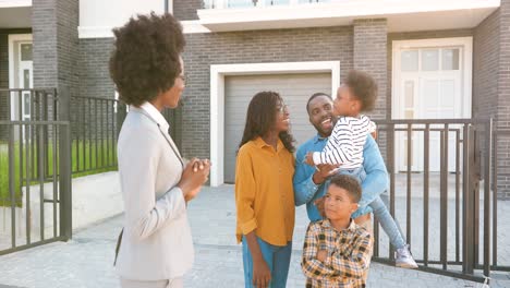 female real-estate handing keys to african american happy family with kids