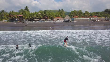 aerial drone shot over surfers enjoying the surf on the coast of el salvador