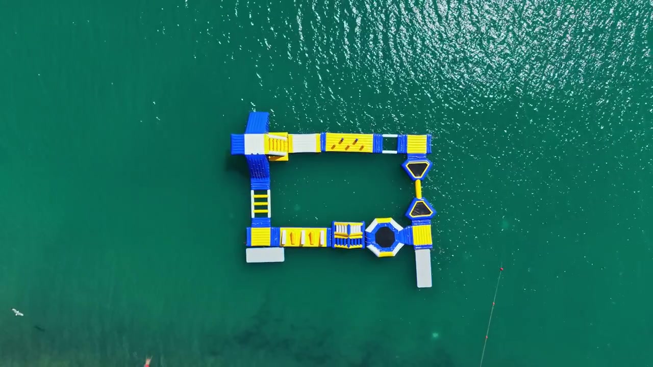 Floating water park with bright colored attractions on clear blue water during the daytime in a warm climate