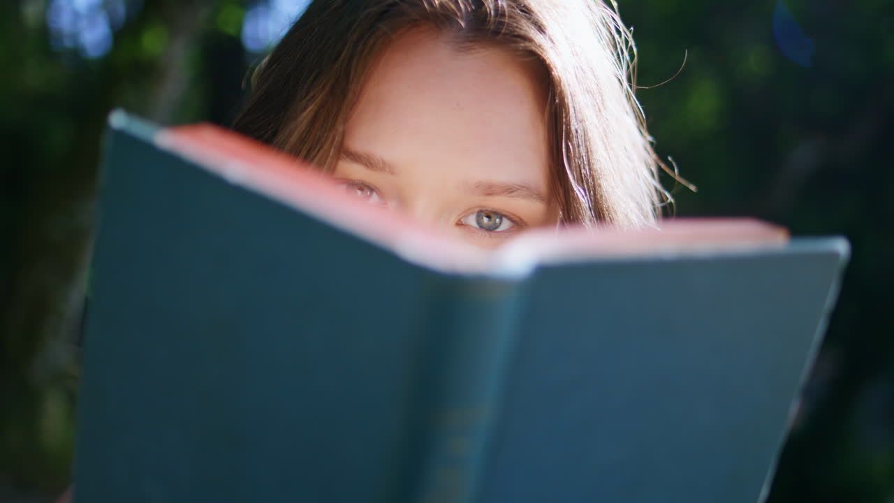 Sunshine woman flipping novel pages in summer closeup. Model looking camera