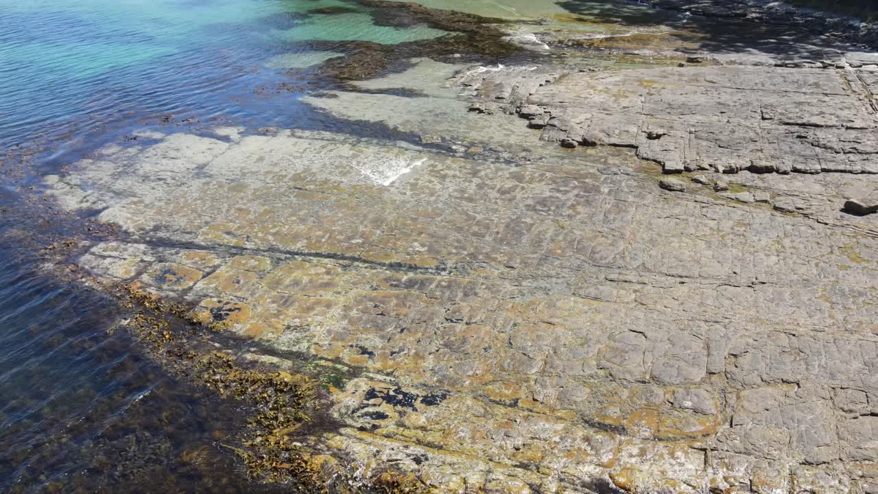 antena de drones sobre rocas con patrones y simetría pavimento teselado tasmania con agua azul tropical