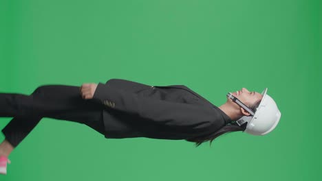 side view of smiling asian female engineer looking around and shaking her head while walking in the green screen studio