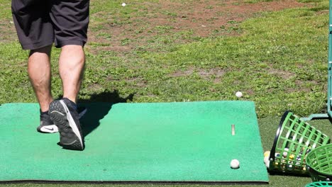 man practicing golf swing on green mat