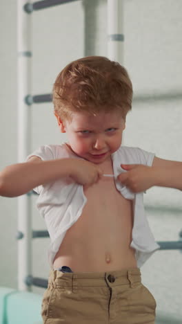 little boy with wet hair in torn t-shirt imagines himself adult fighter slow motion. toddler kid plays dreams to be world boxing champion. funny child