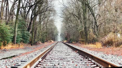 low establishing winter shot on train tracks toward foggy horizon