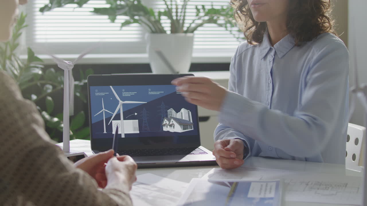 Renewable Energy Engineers Discussing WInd Power Presentation on Laptop