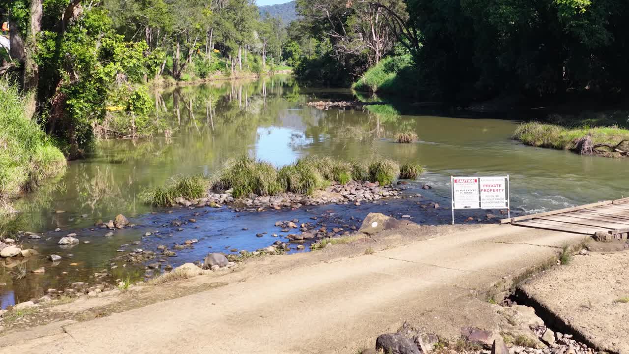 A serene stream flows through a forested area in Uki, NSW, under bright daylight, highlighting natural beauty and tranquility