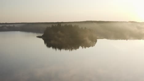 aerial of misty morning above scandinavian lake with forest in background
