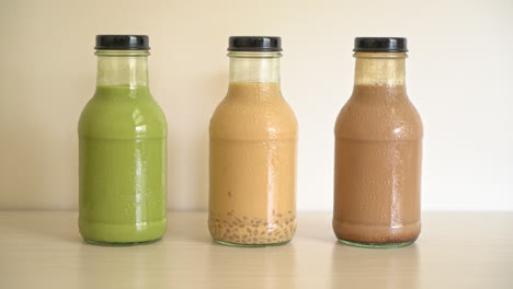 matcha green tea latte, chocolate and milk tea with pudding jelly in glass bottle on the table