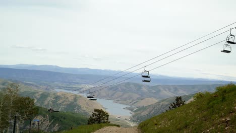 beautiful scenic tilt up shot of deer creek lake on rolling rocky mountain hills from the top of sundance ski resort with ski lifts passing up and down on a warm summer sunny day in utah, usa