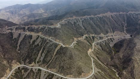 Vista-Aérea-Giratoria:-Carretera-Panorámica-Con-Curvas-En-La-Ladera-De-La-Montaña