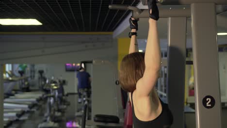 woman doing pull-ups in a gym