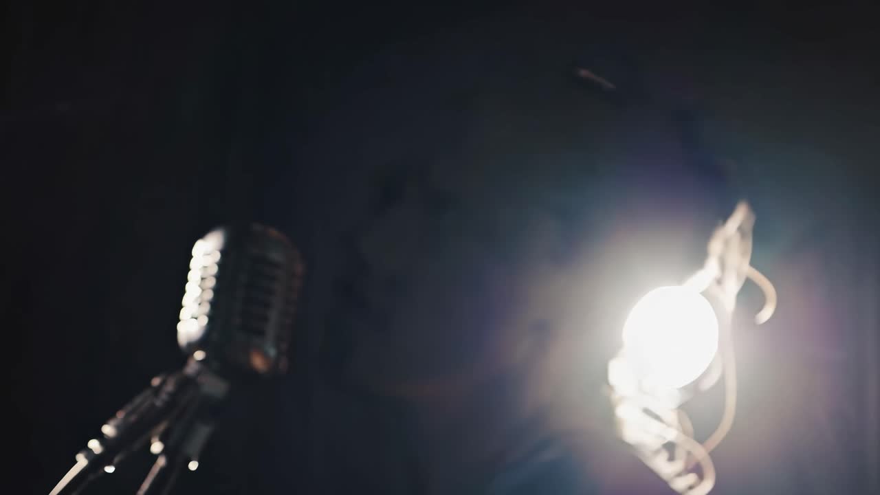 Moody video scene with a close-up, side angle of a singer silhouetted against a bright light