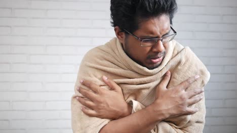 man wrapped in a towel, appearing cold or ill