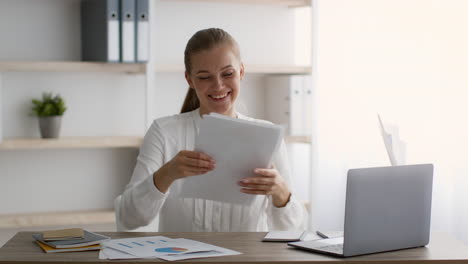 mujer celebrando el éxito con documentos en una oficina