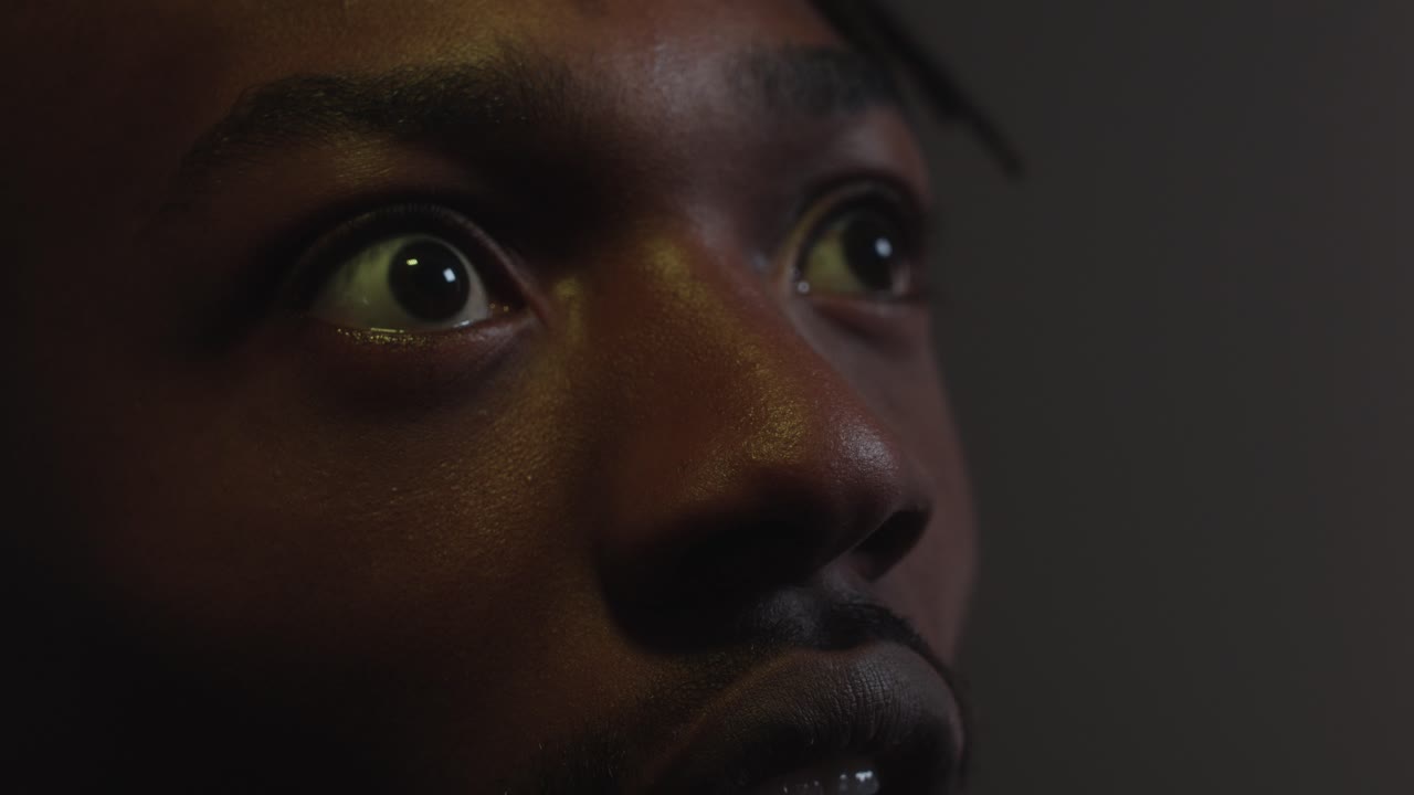 Man reacting shocked an scared by something on the cinema screen in close up