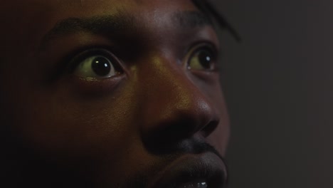 man reacting shocked an scared by something on the cinema screen in close up