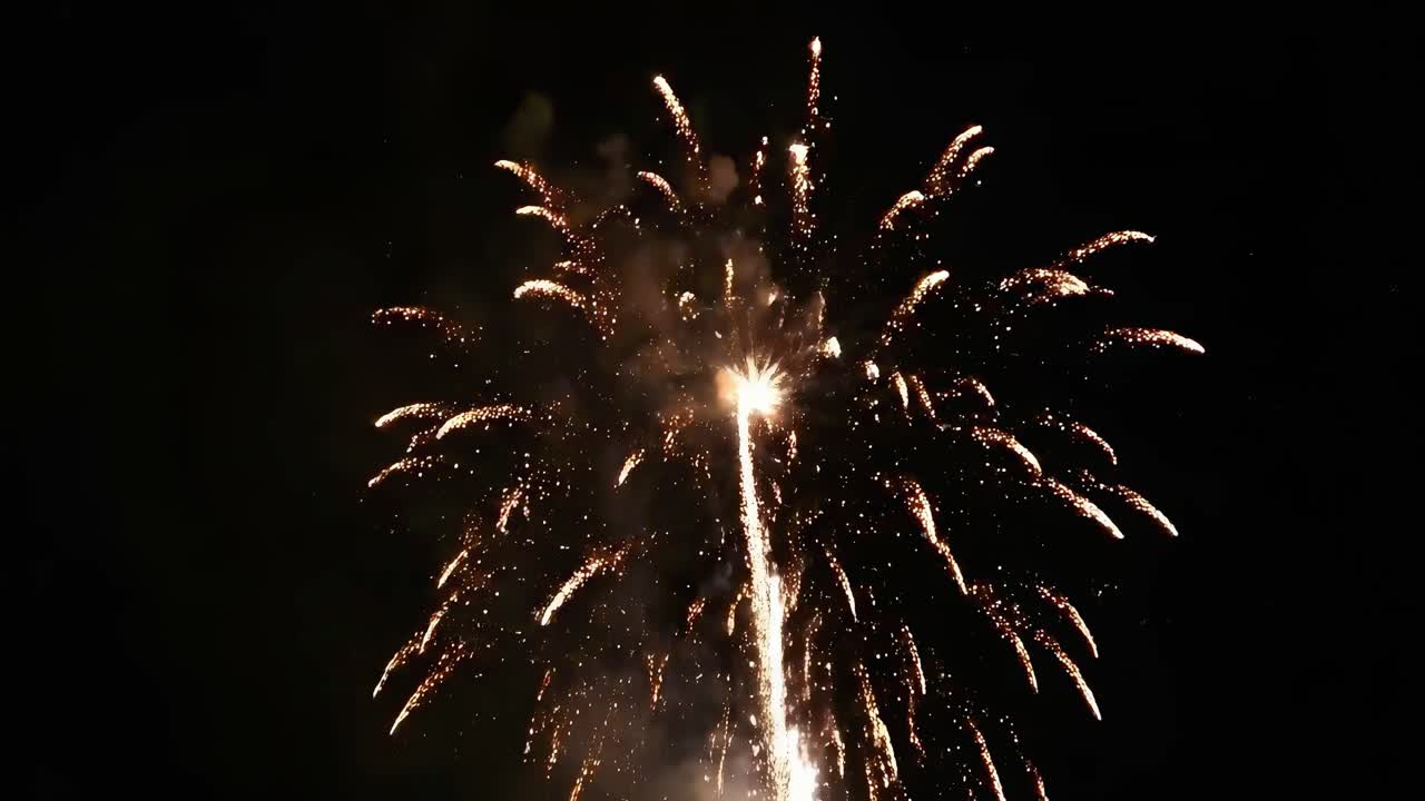 Aerial video of vibrant fireworks exploding against a dark sky, captured from below