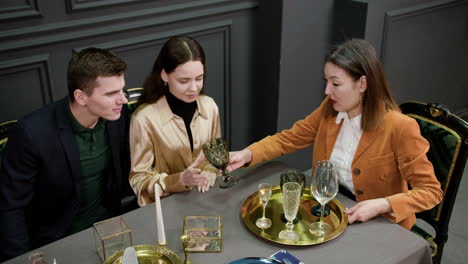 Asian-woman-talking-with-a-couple-sitting-at-a-table